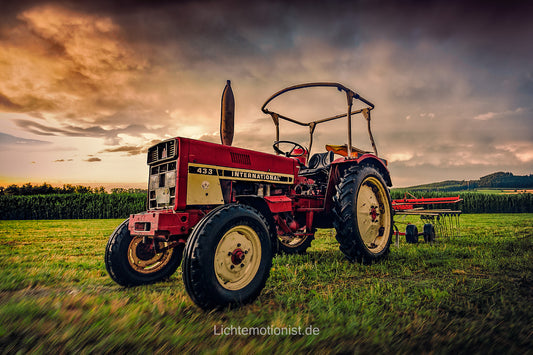 Roter Traktor vor Gewitter und Sonnenuntergang